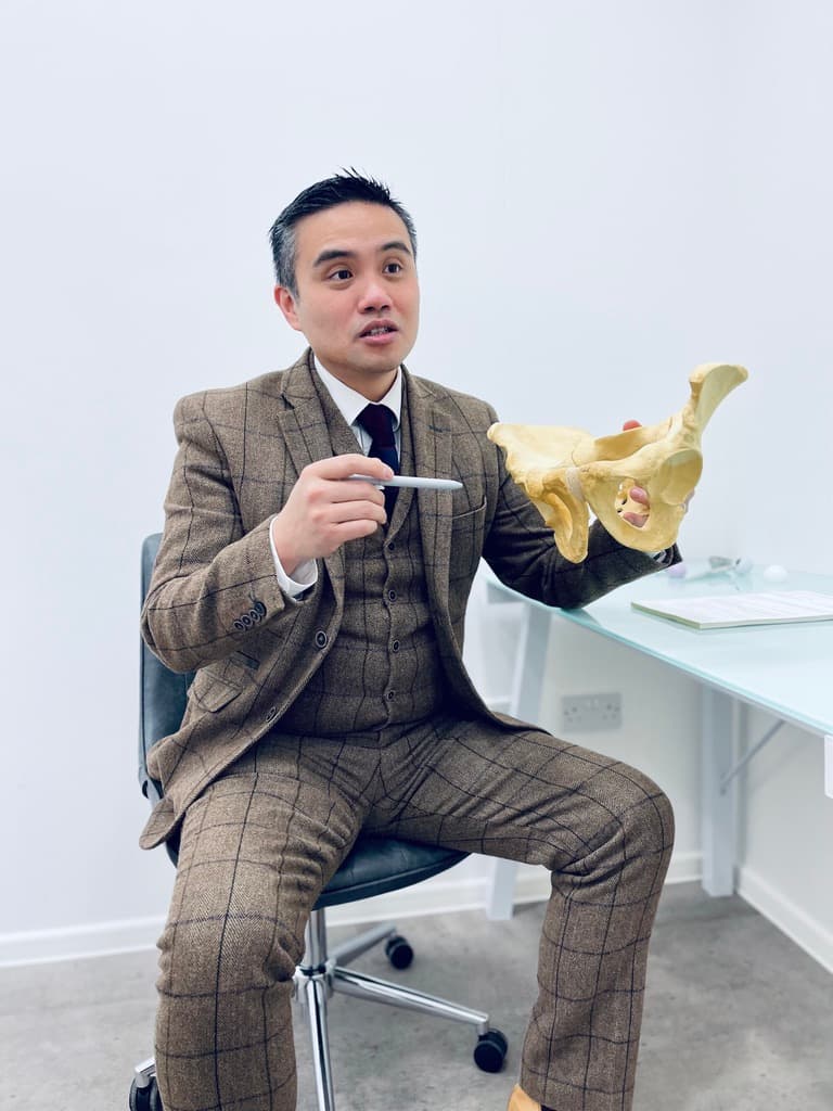Surgeon demonstrating hip anatomy on pelvic model